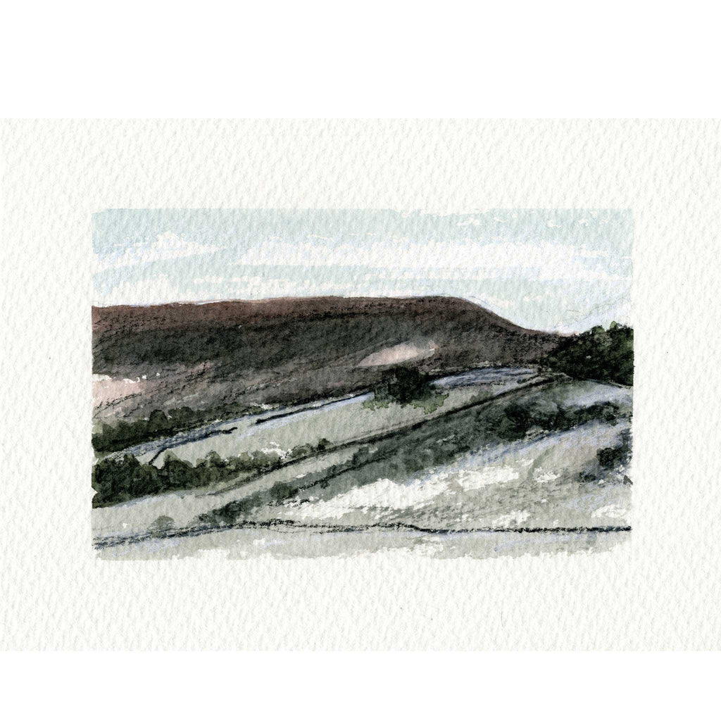 A watercolor landscape painting of rolling hills and fields, shown centered on a textured off-white paper background.